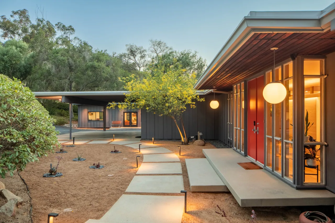 Floating concrete steps lead to the vermilion front doors beneath the redwood soffit