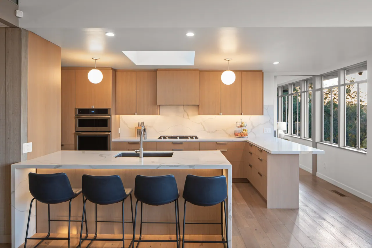 Kitchen with oak cabinetry, stone counters and double wall ovens