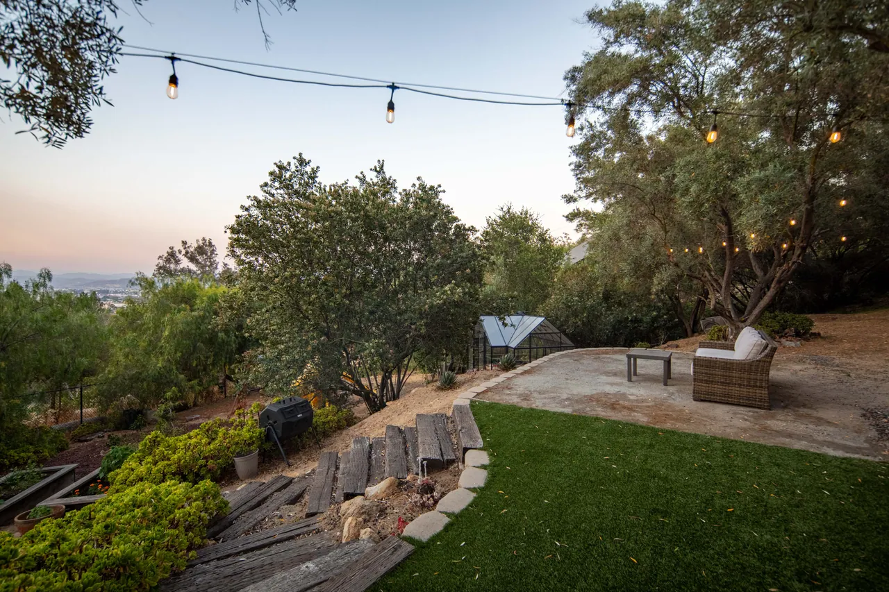 The green and the seating terrace with string lights and a valley view